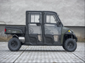 A side view of a green and black Polaris Ranger Crew XP900 Full Hard Cab (2013–PRESENT) utility vehicle parked on pavement, featuring clear hard-sided doors, two-seat rows, four wheels, and a plain light wall in the background.