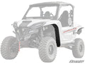 A white Yamaha Wolverine RMAX 1000 with rugged tires is shown. The left front fender features the Low Profile Fender Flare accessory. The SuperATV logo is in the bottom right, with a faded background and rear.