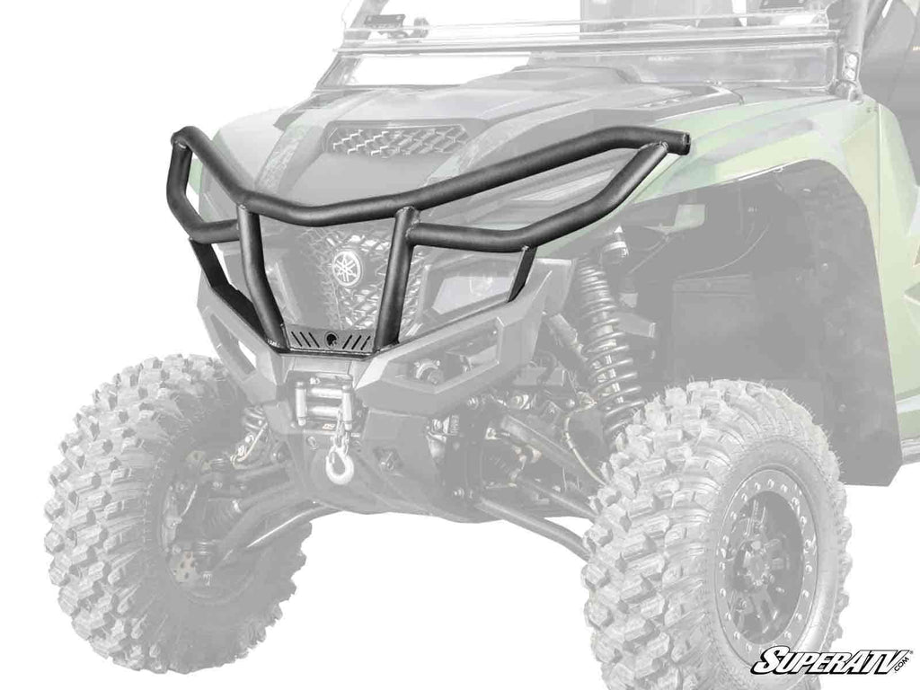The Yamaha Wolverine RMAX Front Bumper, in matte black, is shown installed on a green off-road vehicle with rugged tires. Featuring angular bars, a winch mount, and side protection, the design is highlighted by a faded background vehicle.