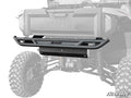 A Yamaha Wolverine RMAX 1000 Rear Bumper is installed on a Yamaha off-road vehicle. The rugged tires and suspension are visible, with “Yamaha” embossed above the bumper. A partial grayscale background draws attention to the bumper.