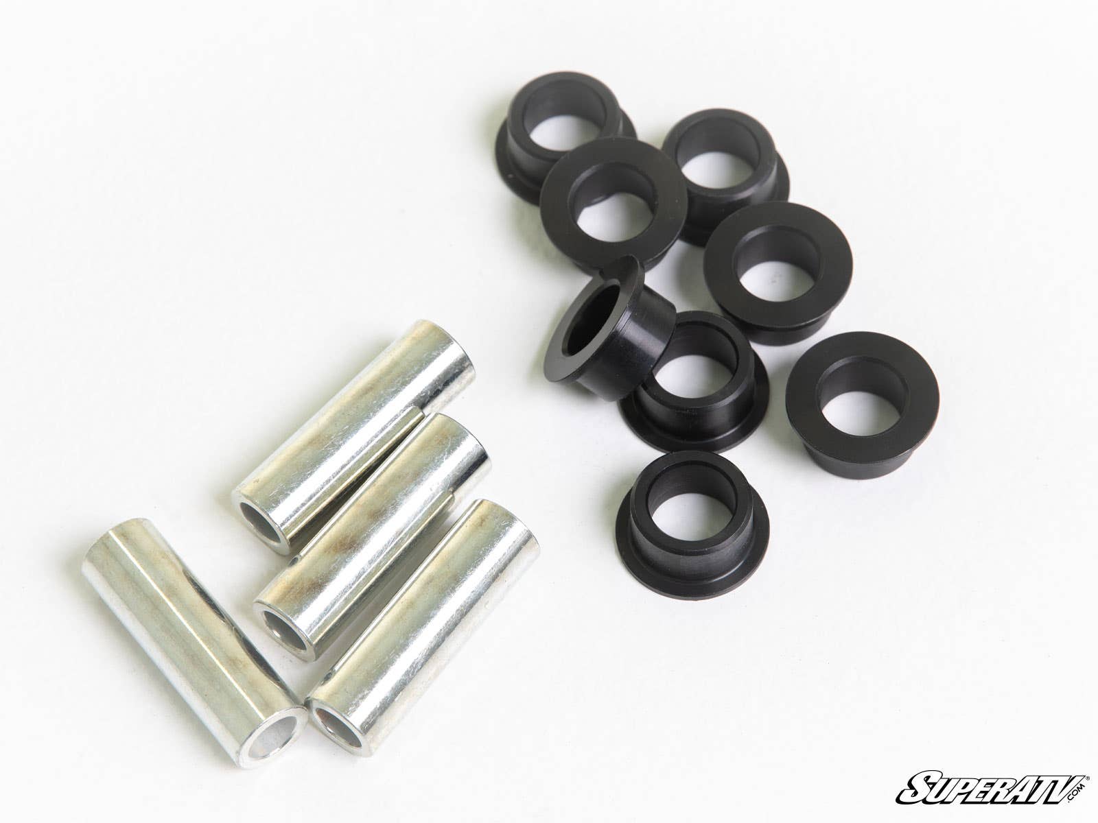 Six shiny metal cylindrical sleeves and six black rubber bushings with flared edges, part of the Yamaha Viking A-Arm Bushings set, are arranged on a white surface. The SuperATV logo is visible in the bottom right corner.