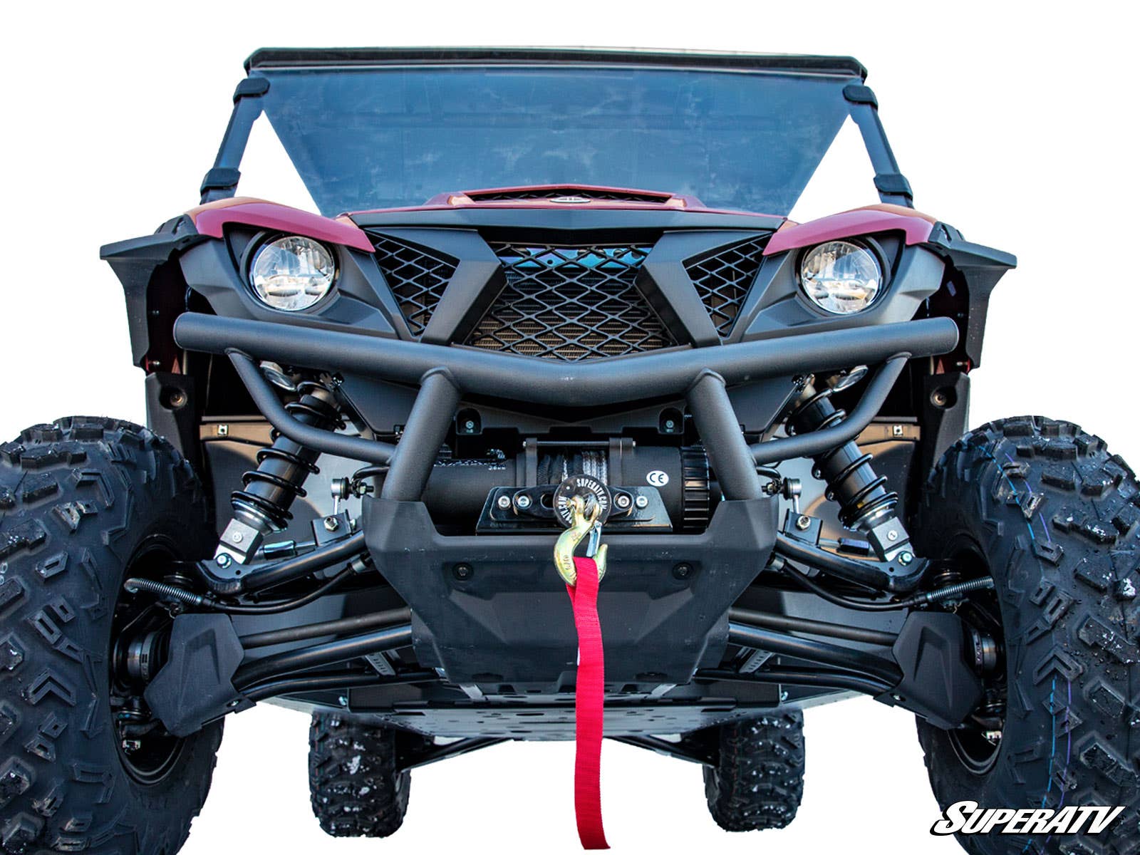 A front-facing Yamaha Wolverine X2 850 with large rugged tires, black grille, visible suspension, red winch strap, and red body on a white background. The SuperATV logo appears bottom right. Features the Winch Mounting Plate.