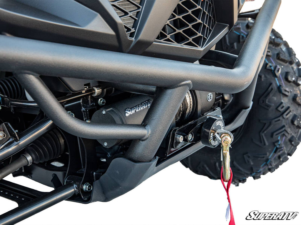 Close-up of a Yamaha Wolverine X4 850 Winch Mounting Plate with a securely mounted winch and cable. Large all-terrain tire, part of the suspension, and the SuperATV logo are visible in the corner.